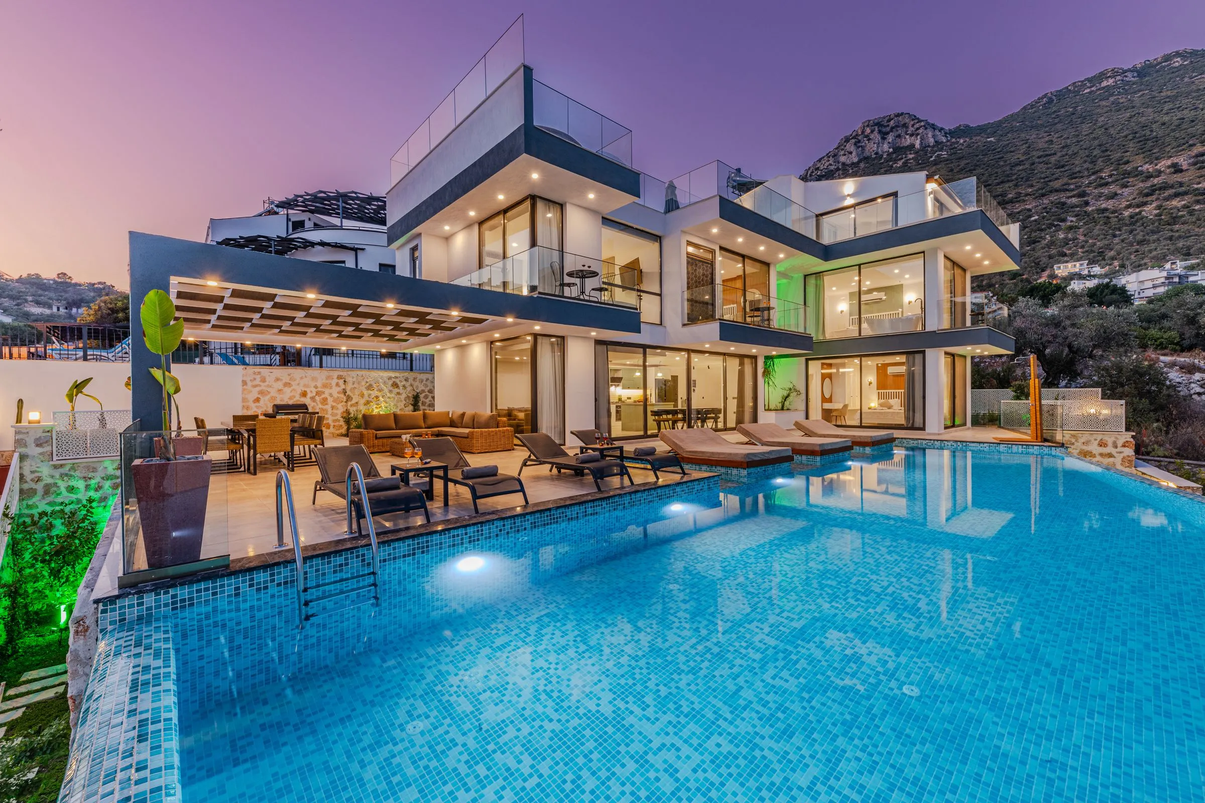 Luxury villa with glass balconies and an infinity pool at dusk